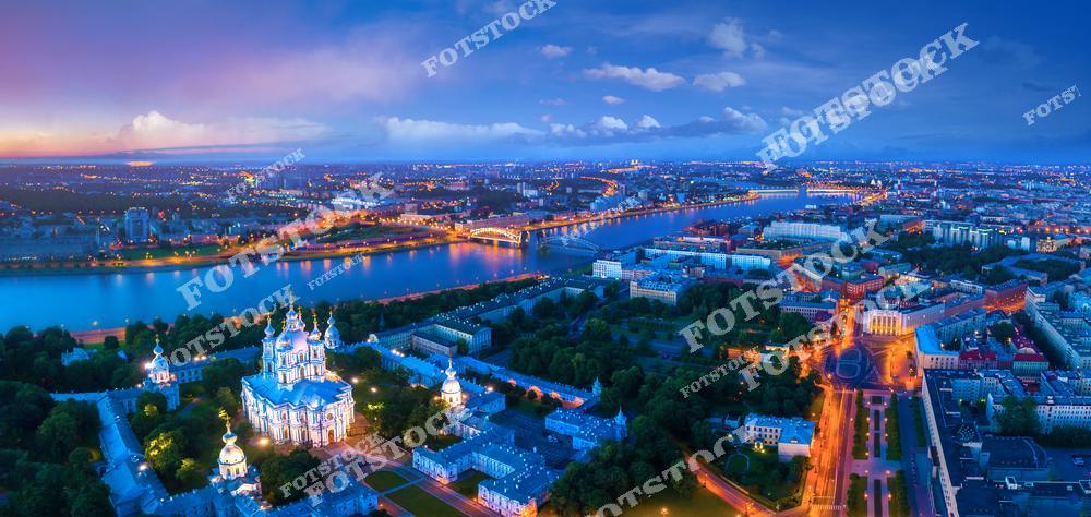Панорамная фотография Санкт-Петербурга с высоты птичьего полета. На снимке виден Смольный собор, река Нева, Большеохтинский мост, улицы исторического центра и архитектурные ансамбли города. Съемка с дрона позволяет оценить масштабы городской застройки, красоту набережных и панораму мостов, раскрывая величие Северной столицы России. Фотография передает уникальную атмосферу Петербурга с высоты, его архитектурное наследие и гармонию городской среды с водной глабу, идеально подходя для туристических публикаций, фотостоков, рекламы, оформления интерьеров и материалов о путешествиях.